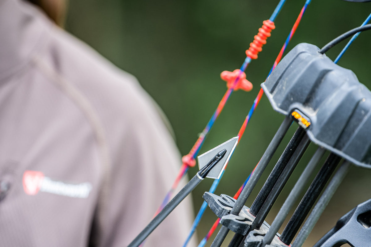 Magnus Stinger Killer Bee 4-Blade broadhead on an arrow beside a bow-mounted quiver